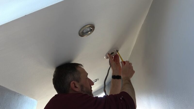 Close-up view of a man installing a fire alarm system
